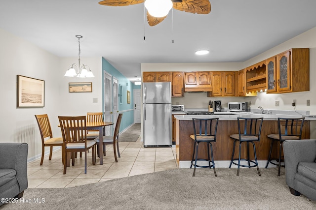 kitchen featuring light tile patterned flooring, pendant lighting, a kitchen breakfast bar, kitchen peninsula, and stainless steel appliances