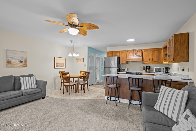 kitchen with pendant lighting, light tile patterned floors, stainless steel fridge, a breakfast bar area, and kitchen peninsula