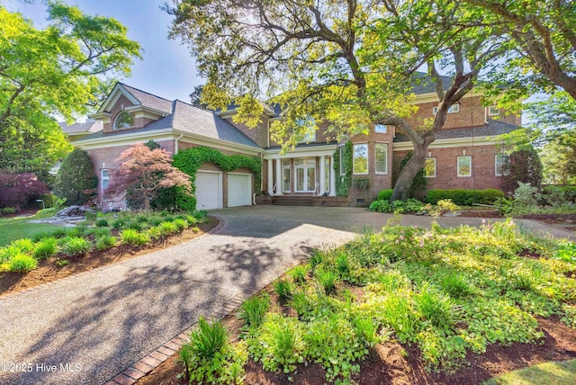 view of front of property with driveway, a shingled roof, brick siding, and an attached garage