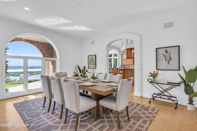 dining room with crown molding, a water view, arched walkways, and visible vents