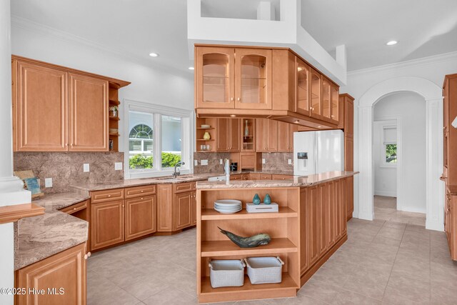 kitchen featuring open shelves, white fridge with ice dispenser, backsplash, light tile patterned floors, and light stone countertops