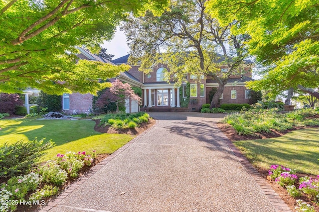 view of front of house featuring a front lawn, french doors, brick siding, and driveway