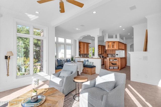 living area with ornate columns, crown molding, baseboards, ceiling fan, and recessed lighting