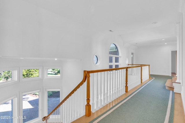 hallway with plenty of natural light, an upstairs landing, a high ceiling, and recessed lighting