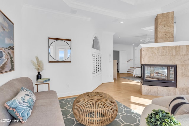 living room with recessed lighting, ornamental molding, a multi sided fireplace, stairs, and wood finished floors