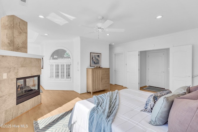 bedroom with a fireplace, ornamental molding, and wood finished floors