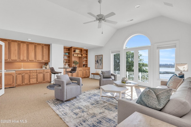 living area featuring light colored carpet, high vaulted ceiling, a ceiling fan, and visible vents