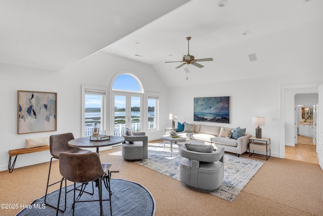 carpeted living room featuring vaulted ceiling, a water view, baseboards, and a ceiling fan