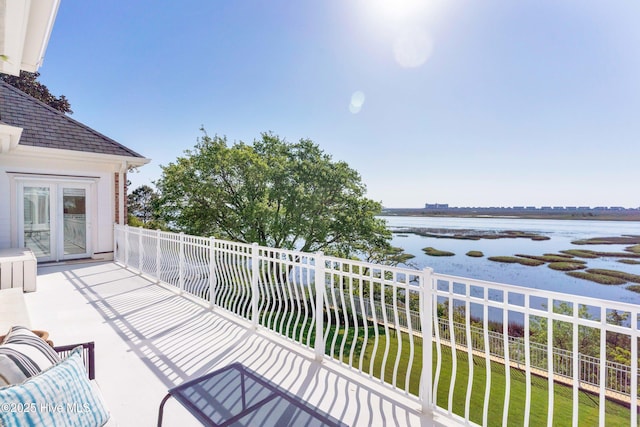 balcony with a water view and french doors