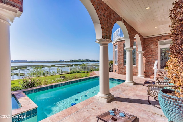 outdoor pool featuring a water view, a patio area, and fence
