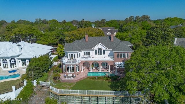 back of property featuring a chimney, an outdoor pool, a fenced backyard, and a balcony