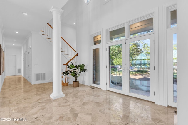 foyer entrance featuring marble finish floor, decorative columns, visible vents, and a towering ceiling