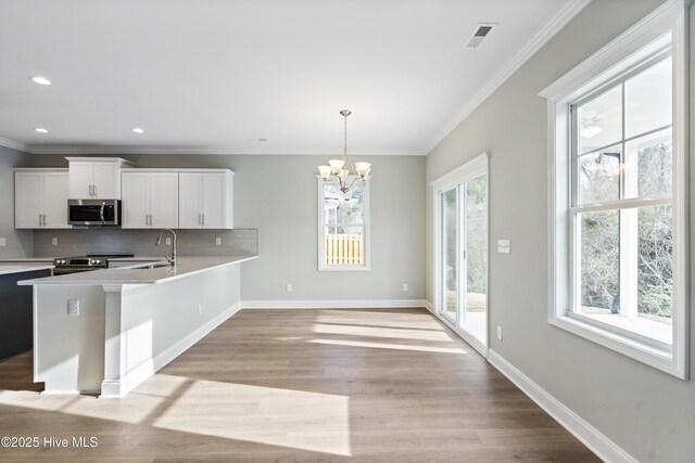 entryway with light wood finished floors, baseboards, visible vents, and crown molding