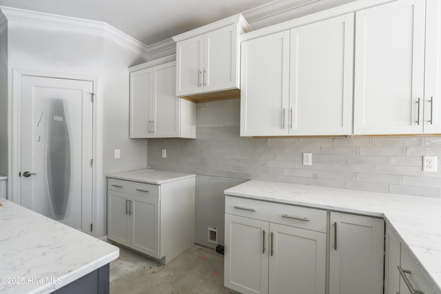 kitchen with tasteful backsplash, ornamental molding, white cabinets, and light stone counters