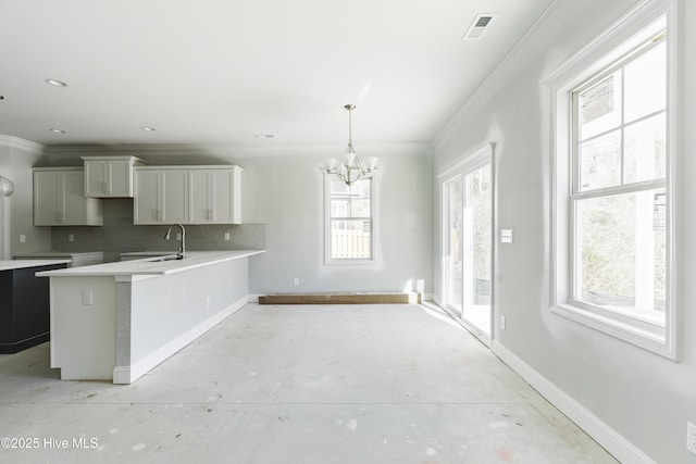 kitchen with tasteful backsplash, sink, hanging light fixtures, ornamental molding, and a notable chandelier