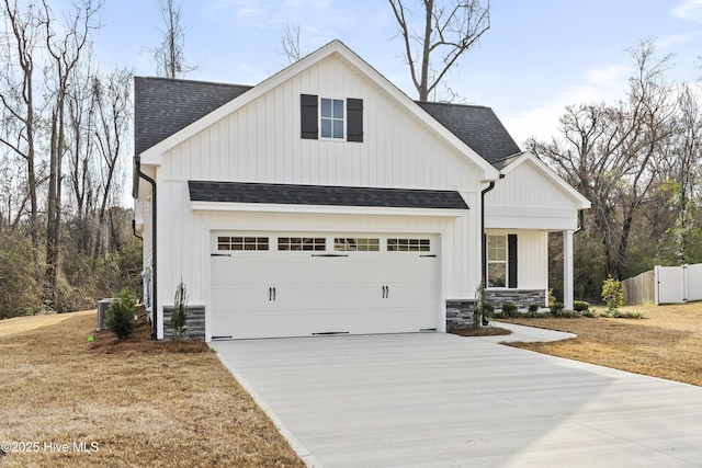 modern farmhouse with central air condition unit, a shingled roof, concrete driveway, fence, and stone siding