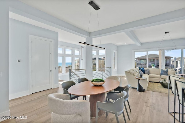 dining room featuring light wood finished floors, baseboards, and beam ceiling