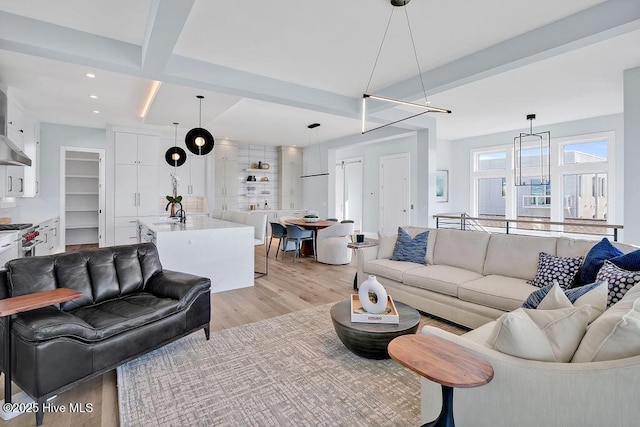living area featuring light wood finished floors, recessed lighting, and beamed ceiling