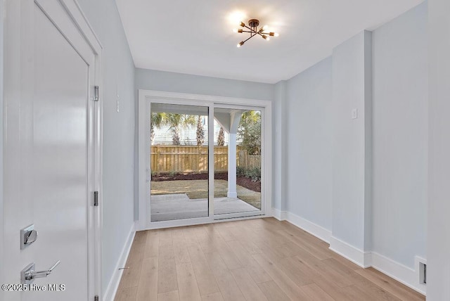 interior space featuring baseboards, a chandelier, and light wood-type flooring