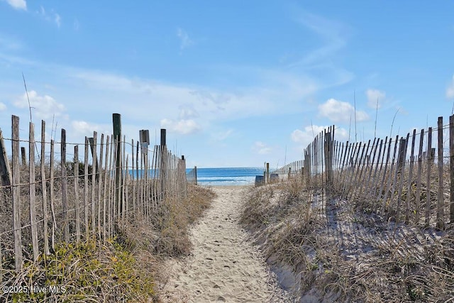 property view of water with fence and a view of the beach