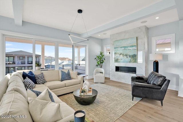 living room featuring light wood finished floors, baseboards, recessed lighting, beamed ceiling, and a high end fireplace