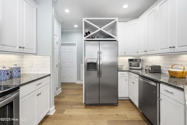 kitchen with stainless steel appliances, white cabinetry, dark stone countertops, and light hardwood / wood-style flooring