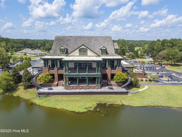 rear view of property featuring a water view, a balcony, and a yard