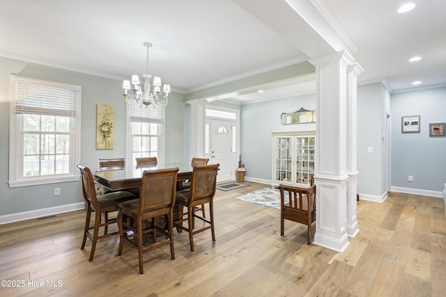 dining room featuring a notable chandelier, light wood-type flooring, ornamental molding, and ornate columns