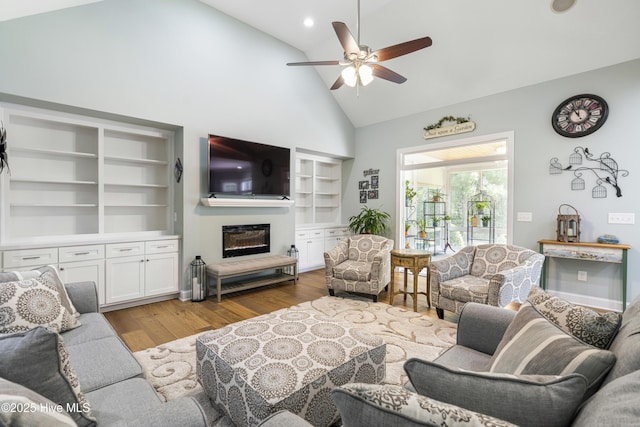 living room featuring built in shelves, ceiling fan, high vaulted ceiling, and light hardwood / wood-style floors