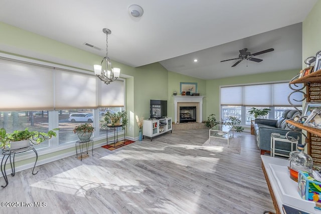 living room featuring lofted ceiling, ceiling fan with notable chandelier, and light hardwood / wood-style flooring