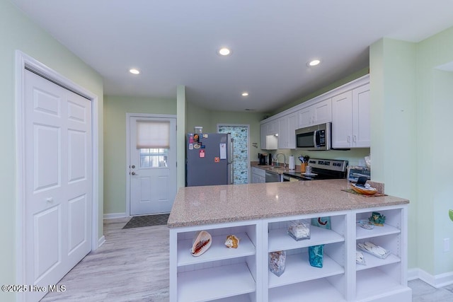 kitchen featuring sink, white cabinetry, kitchen peninsula, stainless steel appliances, and light hardwood / wood-style floors