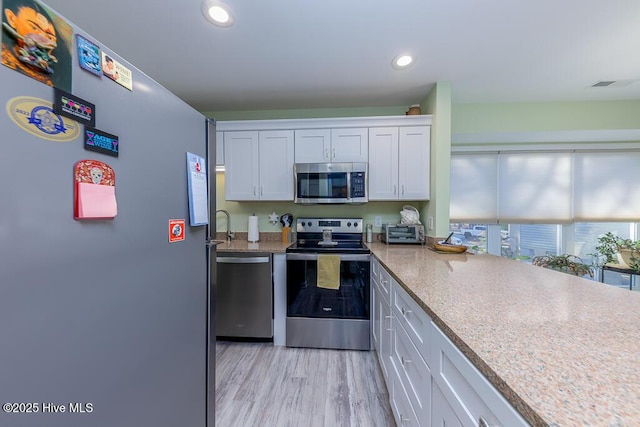 kitchen featuring white cabinetry, light hardwood / wood-style floors, and appliances with stainless steel finishes