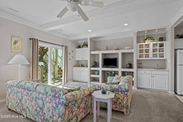 carpeted living room with sink, beam ceiling, built in features, and ceiling fan