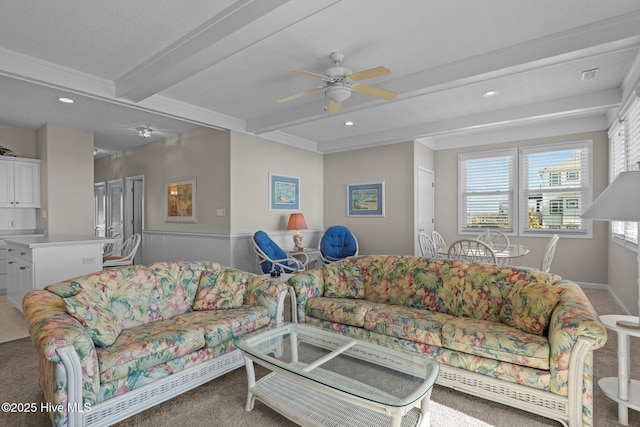 carpeted living room with beamed ceiling, crown molding, and ceiling fan