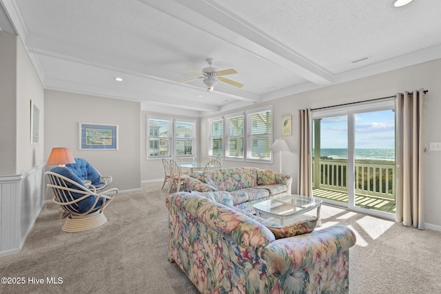 living room with a water view, light colored carpet, a textured ceiling, and beam ceiling