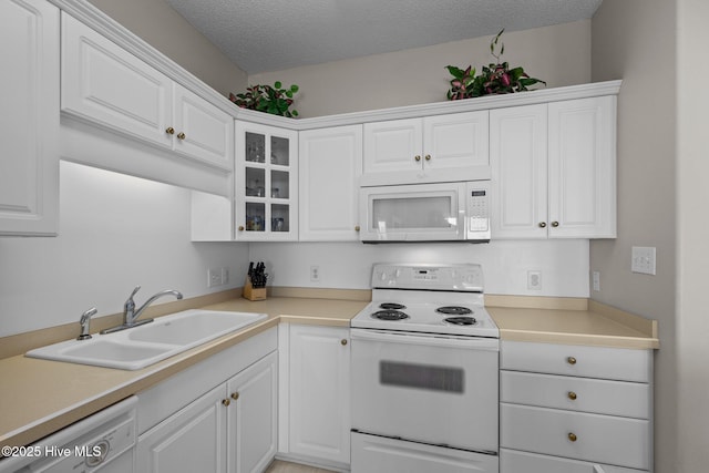 kitchen featuring white appliances, sink, a textured ceiling, and white cabinets