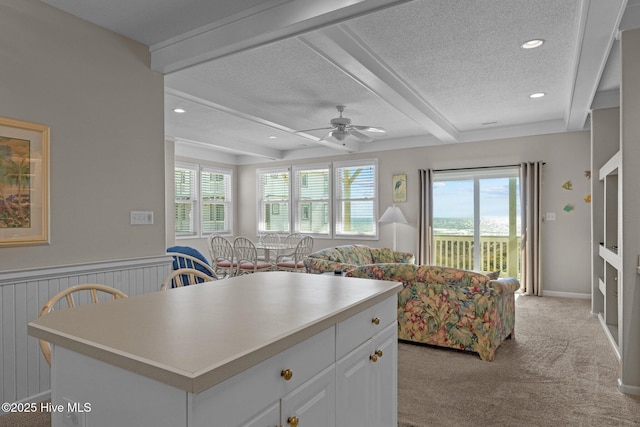 kitchen featuring white cabinets, beam ceiling, a center island, a healthy amount of sunlight, and a textured ceiling