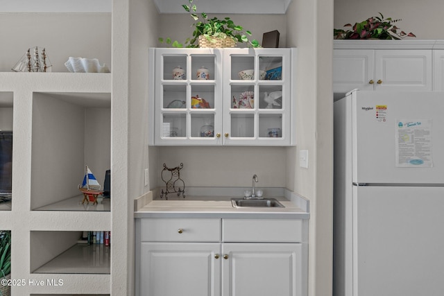 bar with sink, white cabinets, and white refrigerator