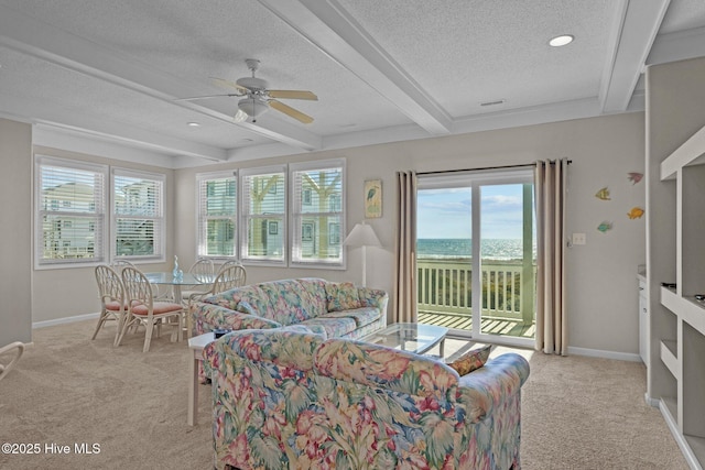 living room with beam ceiling, light colored carpet, a textured ceiling, and a water view