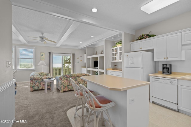 kitchen featuring white appliances, white cabinetry, a kitchen breakfast bar, a kitchen island, and beamed ceiling