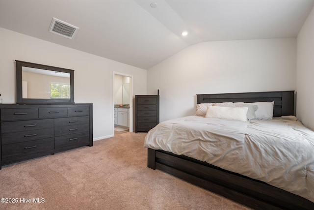 bedroom with lofted ceiling, connected bathroom, and light colored carpet