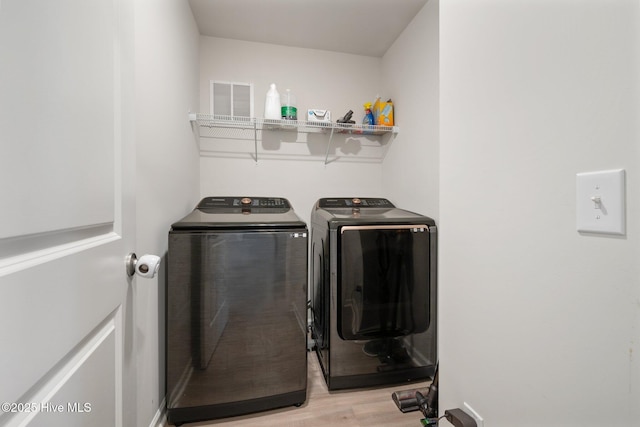 clothes washing area with independent washer and dryer and light hardwood / wood-style floors