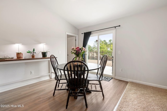 dining area featuring lofted ceiling and wood-type flooring