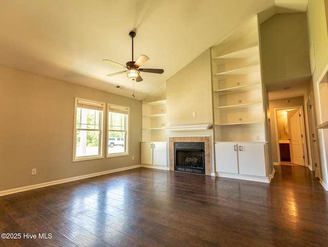 unfurnished living room with ceiling fan, high vaulted ceiling, baseboards, a tile fireplace, and dark wood-style floors