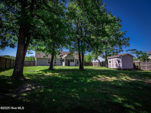 view of yard with a storage unit, a fenced backyard, and an outbuilding