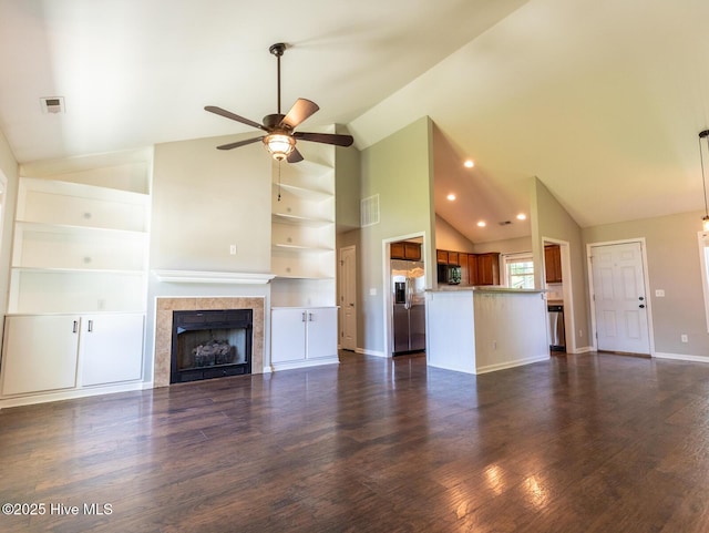 unfurnished living room featuring high vaulted ceiling, dark wood finished floors, a tiled fireplace, a ceiling fan, and visible vents