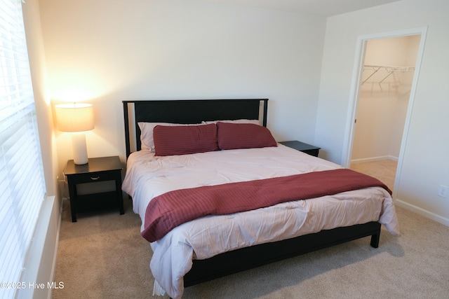 bedroom featuring a walk in closet, light carpet, and a closet