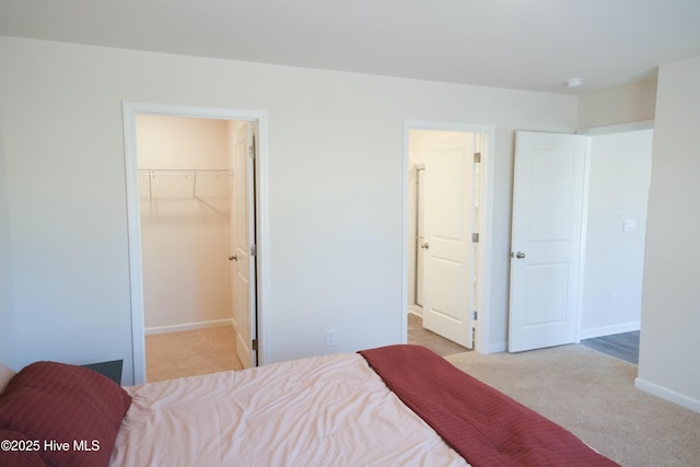 bedroom with light carpet, a walk in closet, and a closet