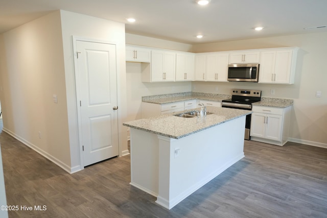 kitchen with sink, white cabinetry, an island with sink, stainless steel appliances, and light stone countertops