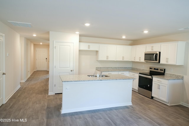 kitchen featuring appliances with stainless steel finishes, a kitchen island with sink, white cabinets, and light stone counters